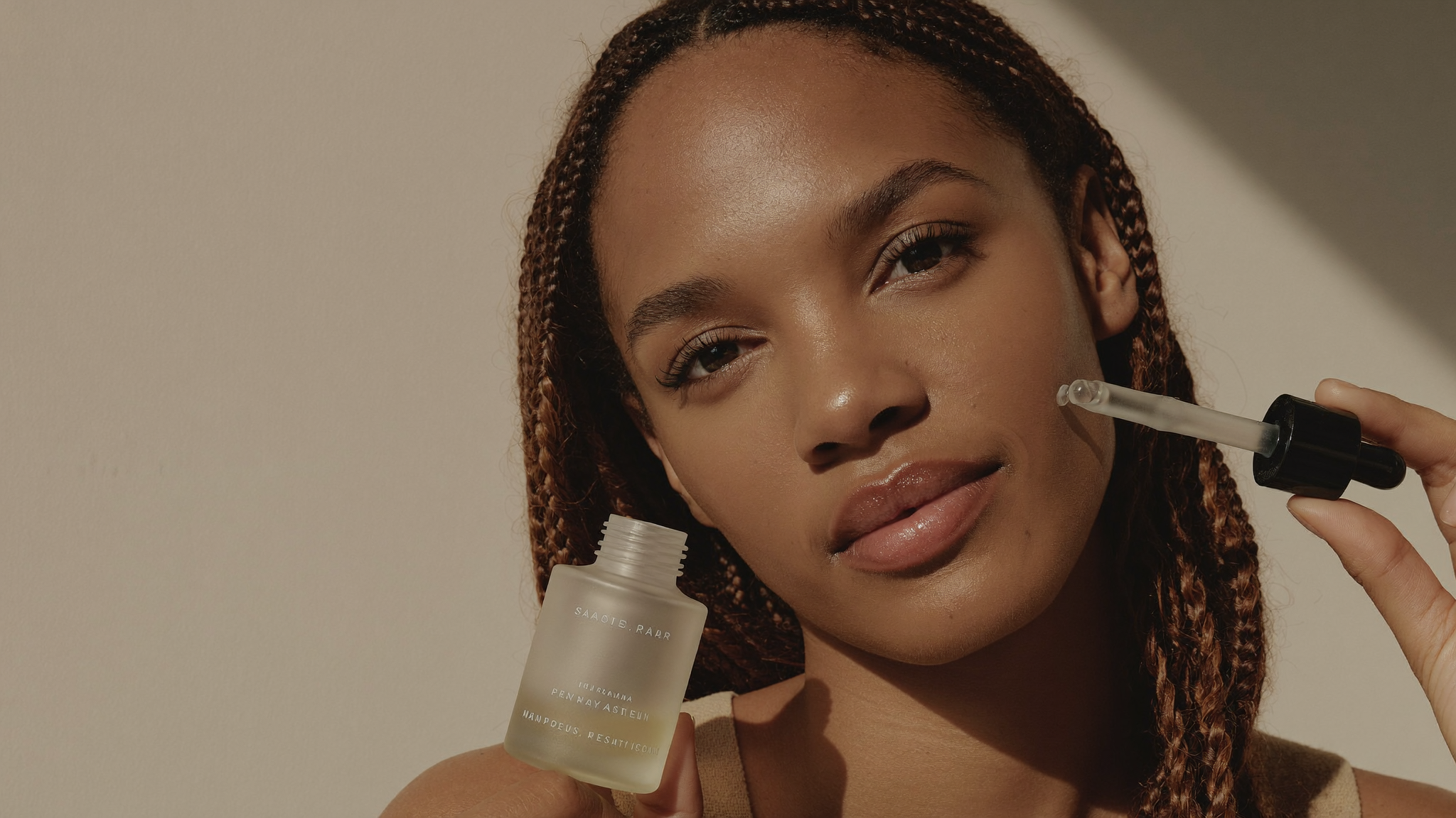 A woman with radiant, glowing skin holding the Bare Ritual Bright C Serum